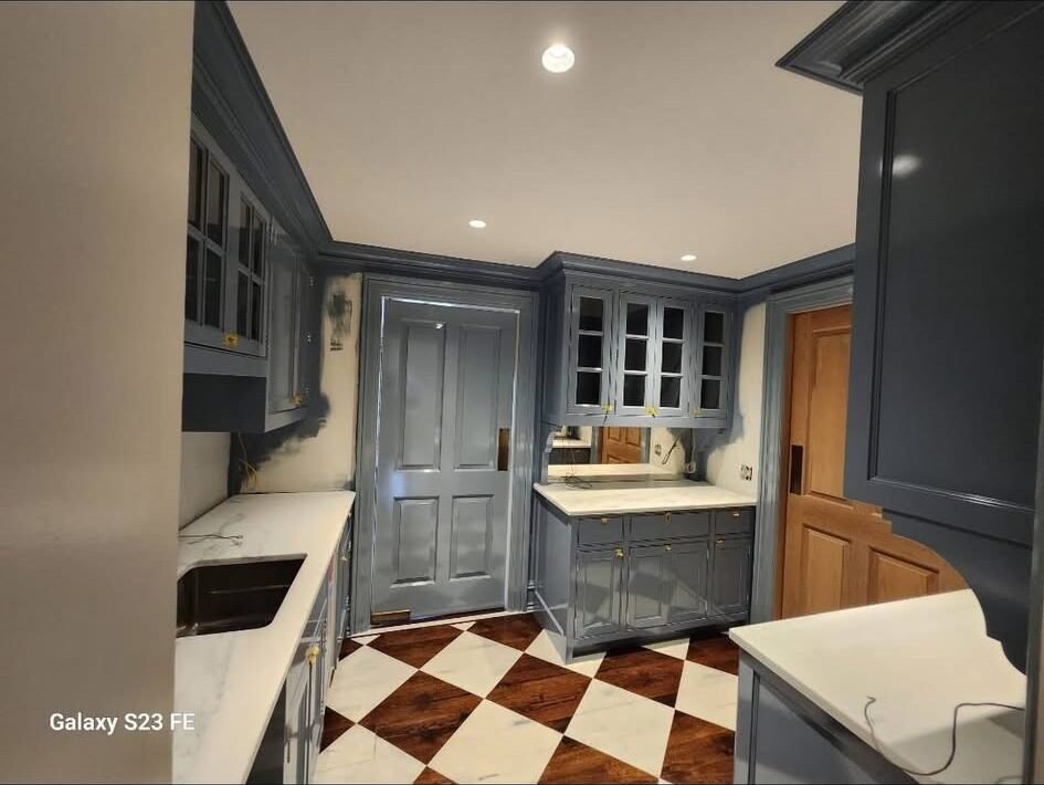 Blue-gray painted kitchen cabinets and door with checkerboard floor in a New Canaan CT home