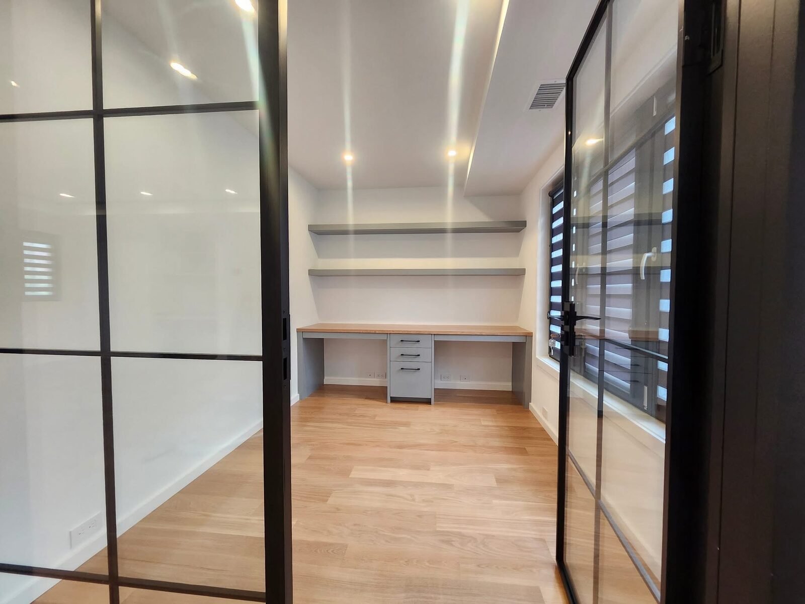Freshly painted office space with glass partition doors and built-in desk