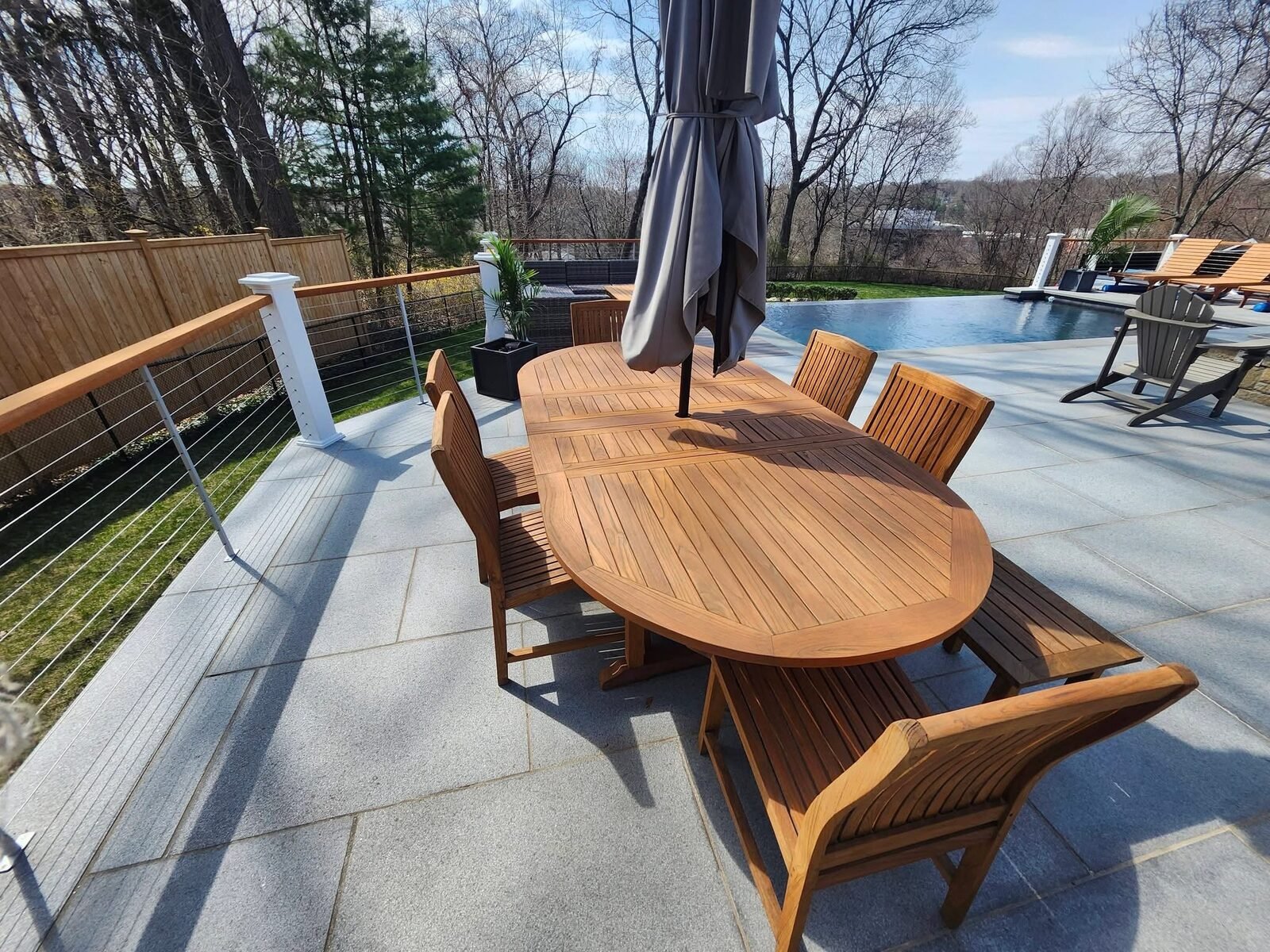Refinished teak outdoor dining table and chairs on a pool patio