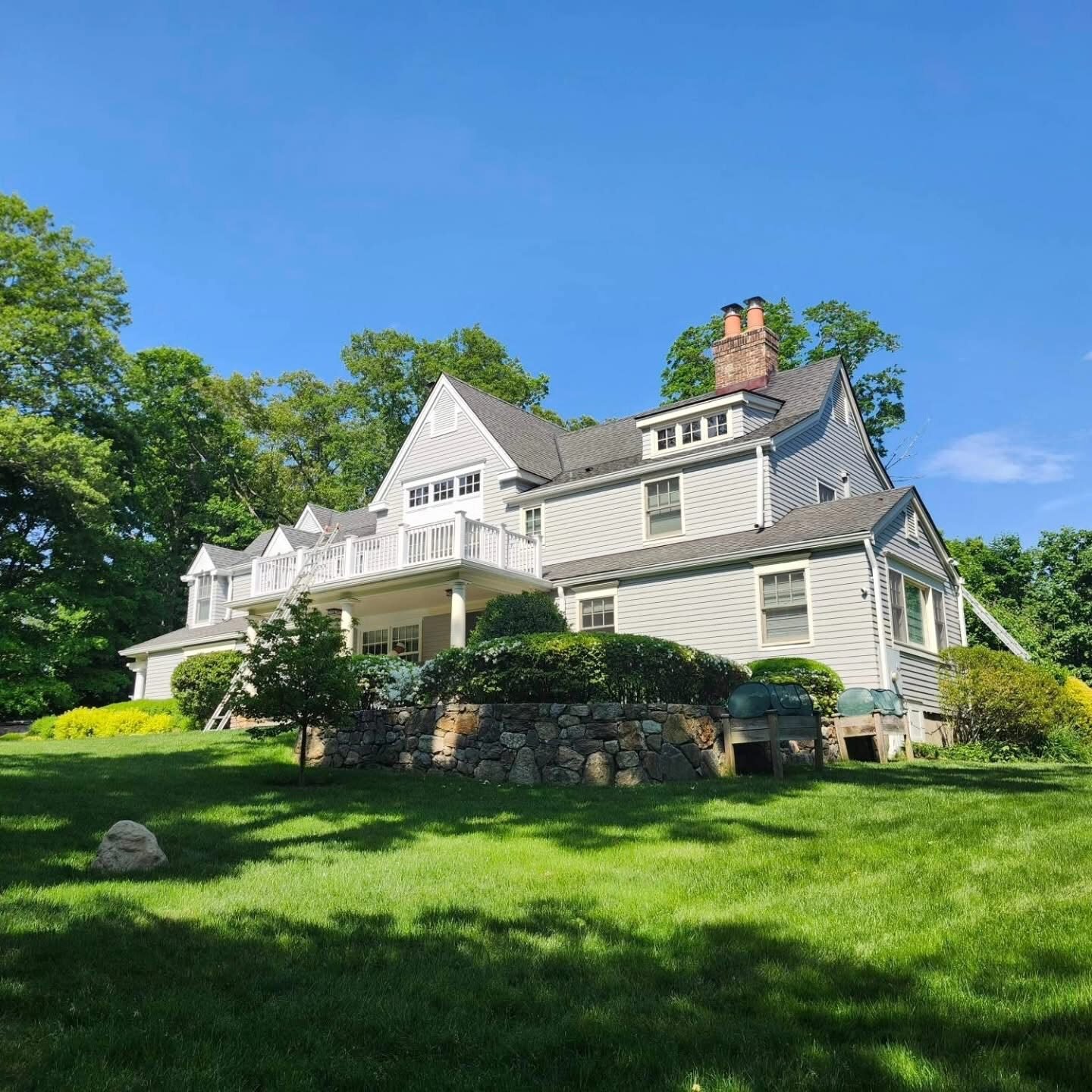 Newly painted gray colonial home with white trim and ladders on site in Greenwich CT