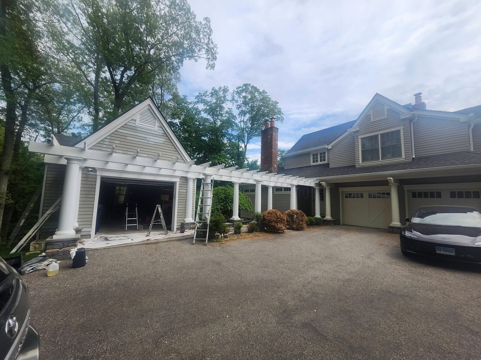 Exterior painting in progress on a garage and white pergola at a Stamford CT home