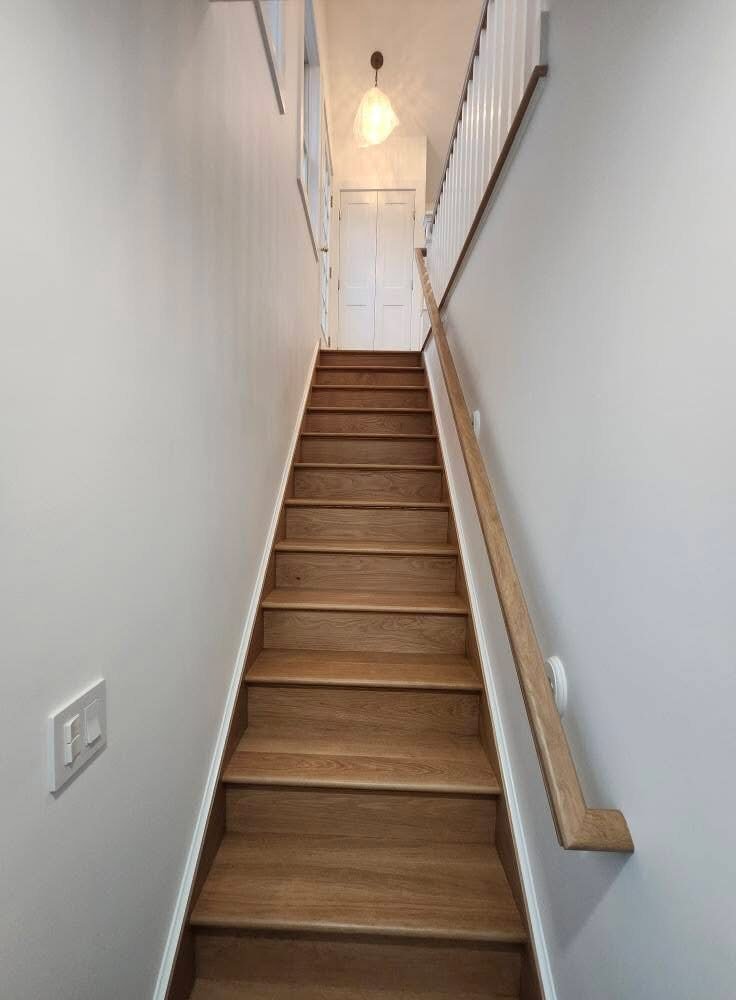 Narrow staircase with freshly painted white walls and oak treads in a Danbury CT home