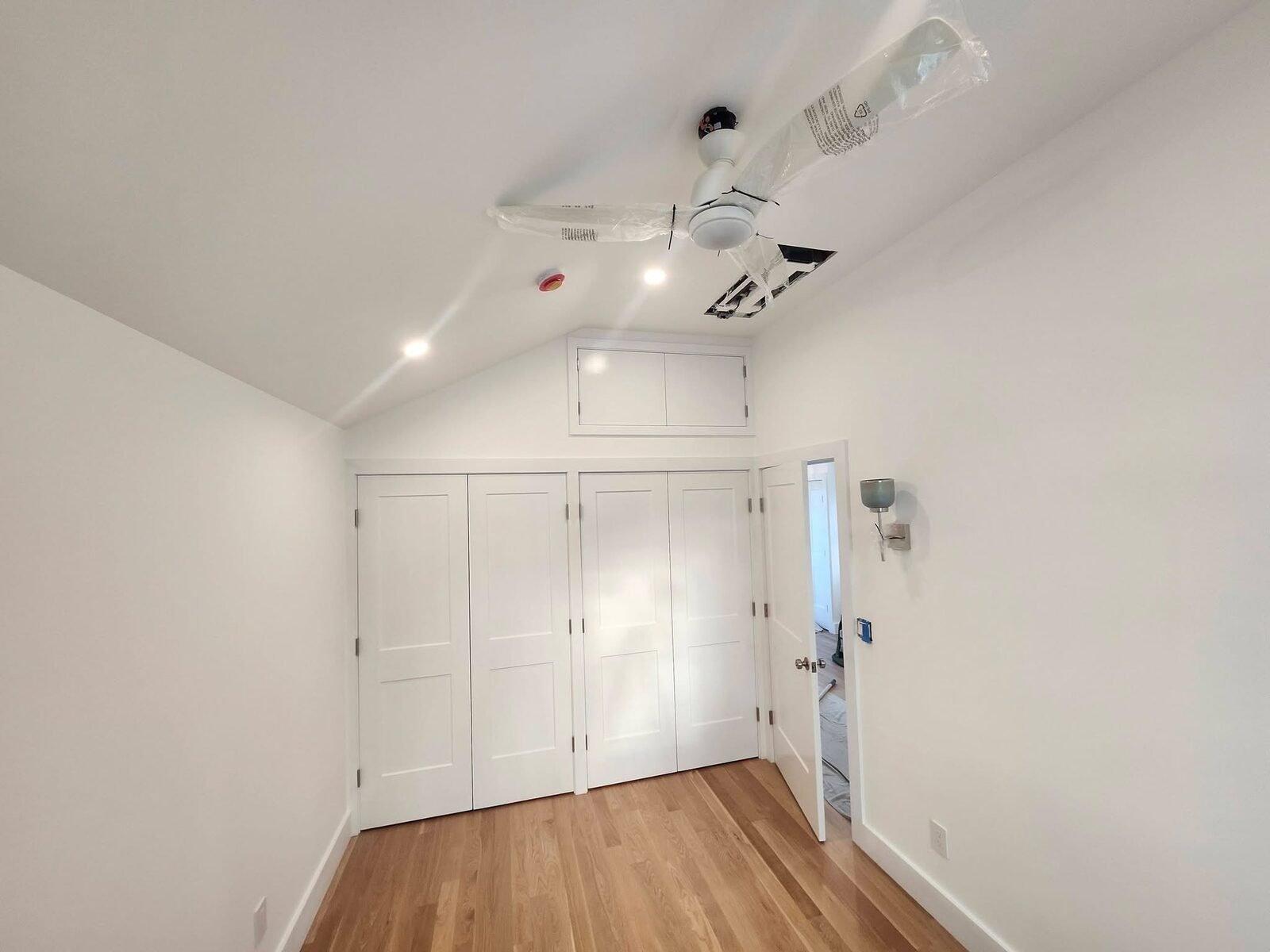 Bedroom with freshly painted white walls, closet doors and vaulted ceiling