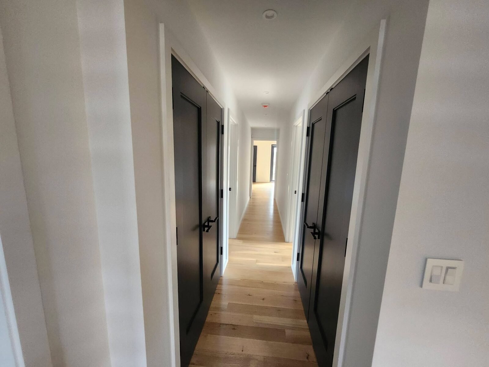Hallway with white walls and painted black doors in a Fairfield County CT home