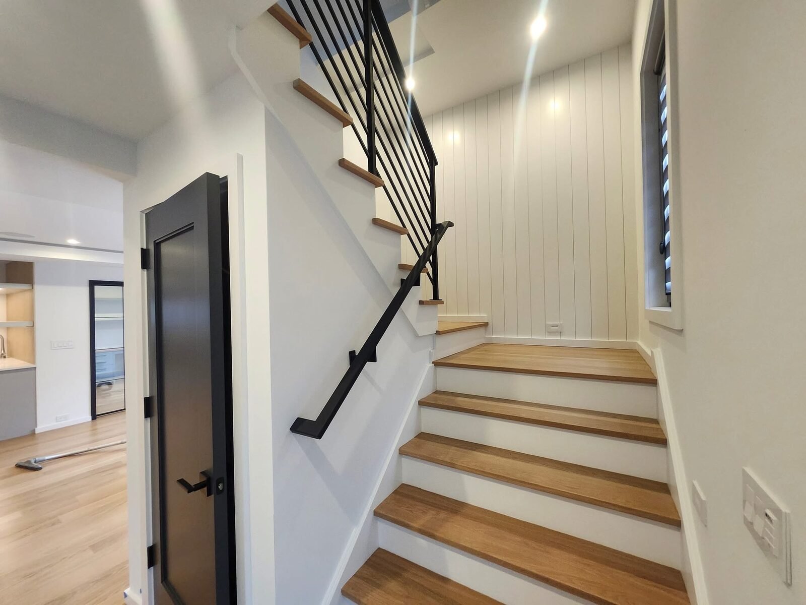 Staircase with white shiplap wall and black metal railing in a Ridgefield CT home