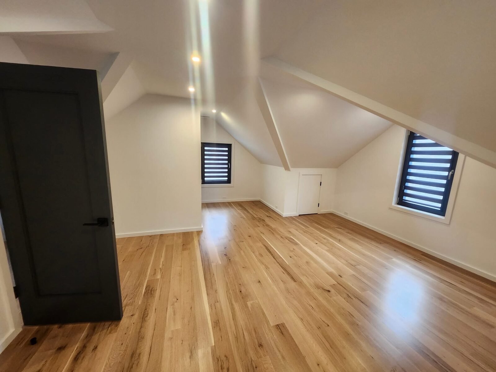 Attic bonus room with freshly painted white walls and sloped ceilings in a Shelton CT home