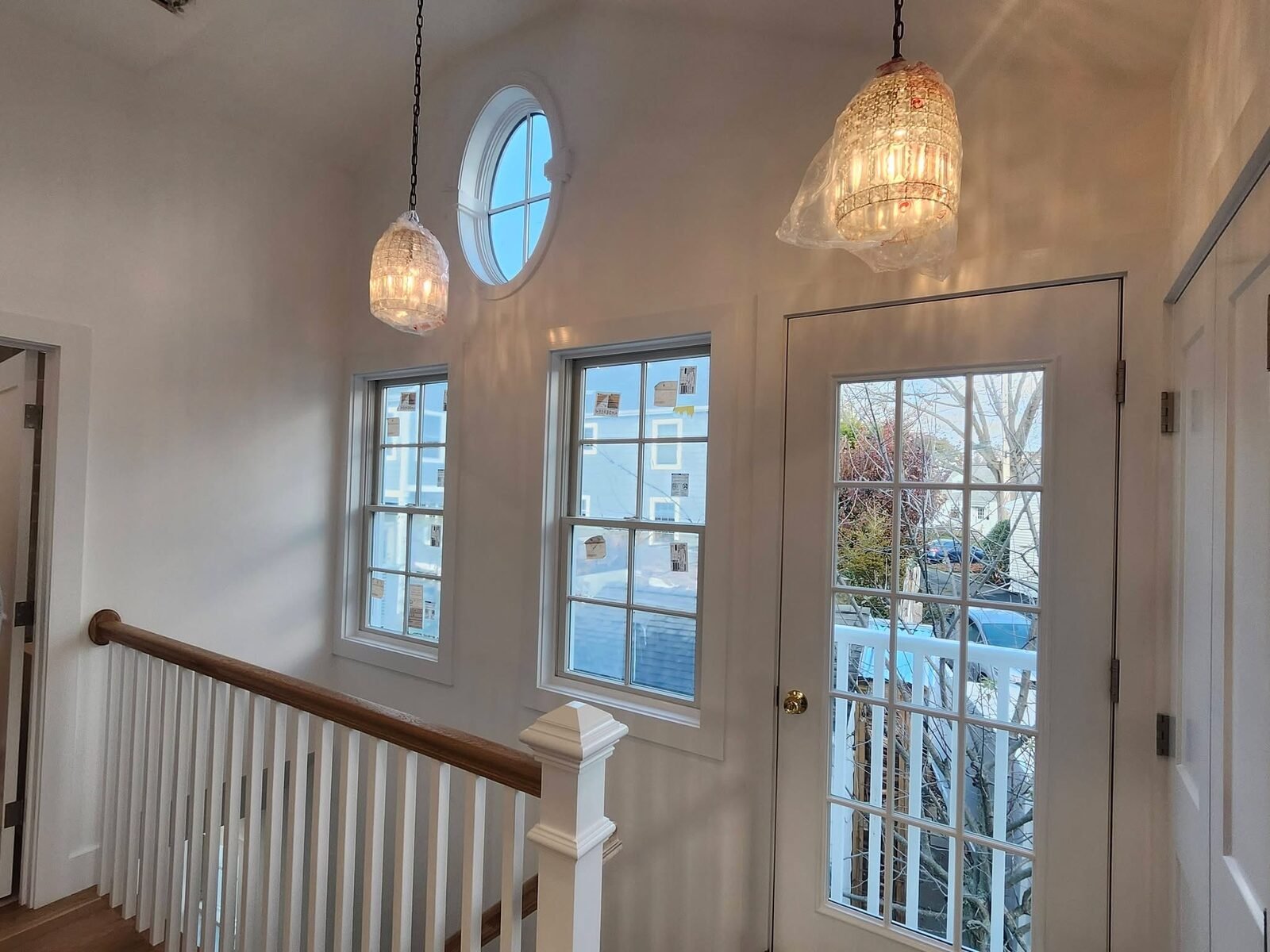 Freshly painted white stairwell landing with round window in a Wilton CT home